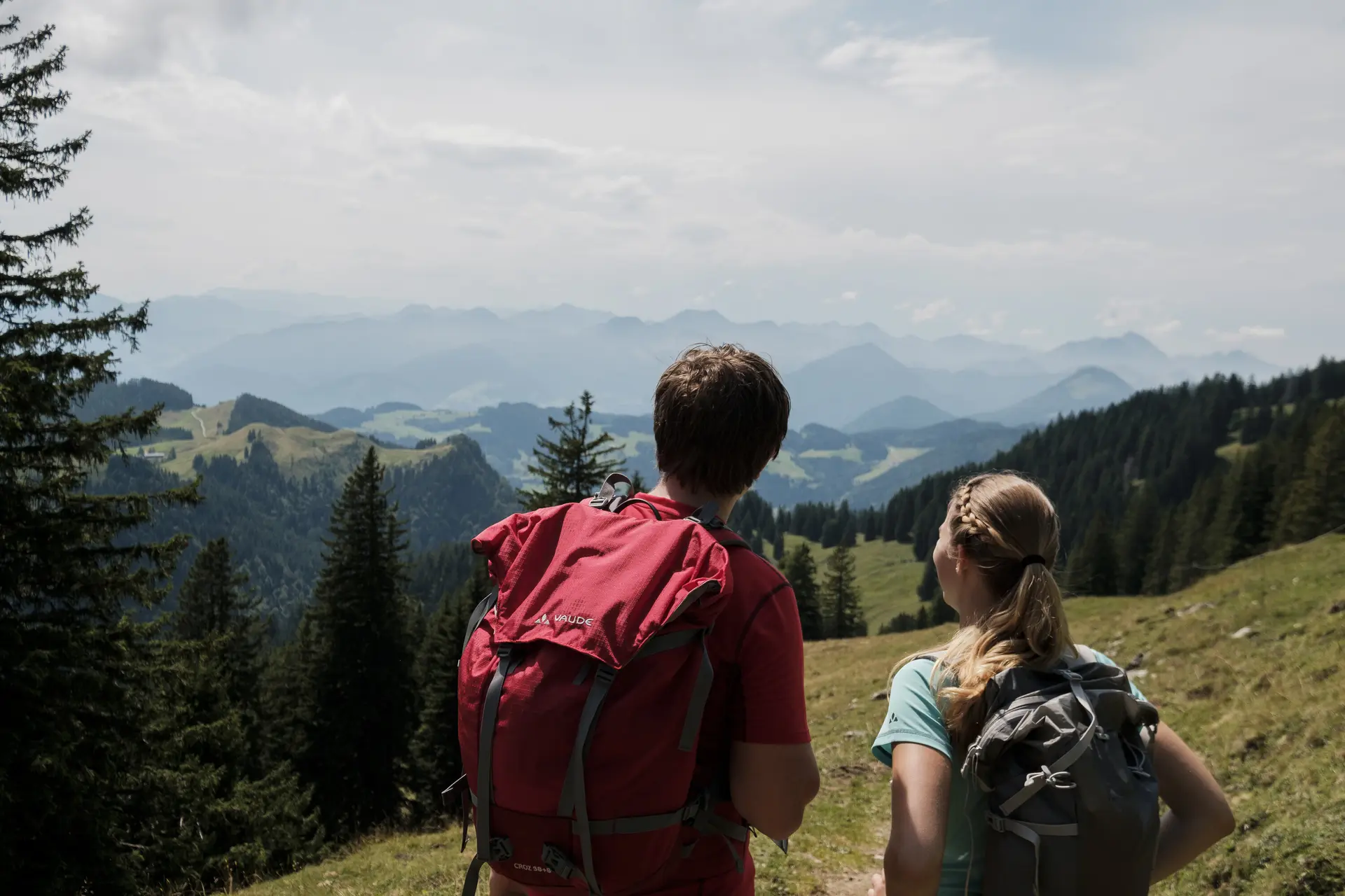 Ein Mann und eine Frau beim Wandern Wanderer in den Chiemgauer Alpen - sie genießen den Ausblick über mehrere Gipfel. | © DAV/Hans Herbig